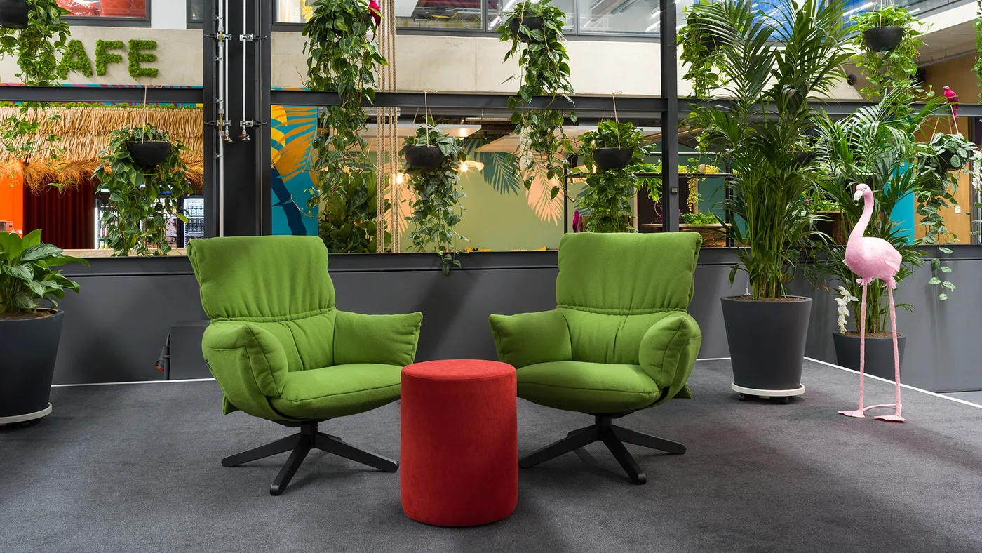 Grüne Loungesessel, Palmen und Flamingo vor dem Café-Schriftzug