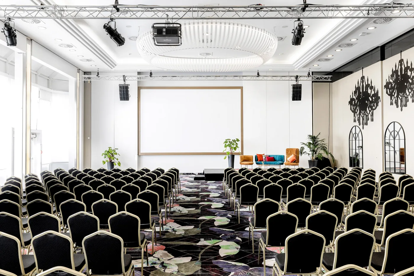 Blick durch die Reihen auf Bühne, Lounge-Sofa und Leinwand